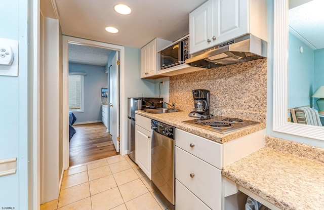 kitchen featuring light wood-type flooring, tasteful backsplash, sink, stainless steel appliances, and white cabinetry