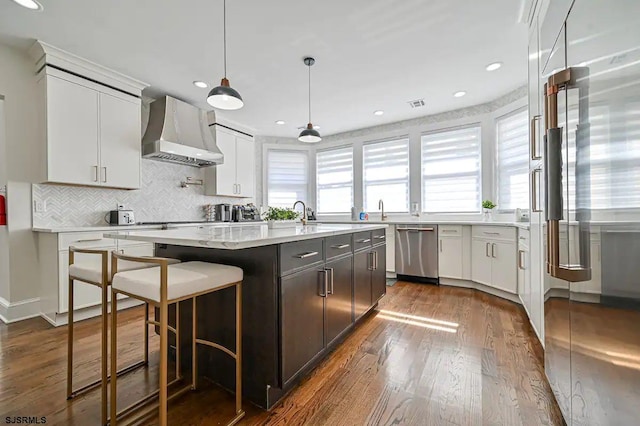 kitchen featuring wall chimney range hood, a center island, stainless steel appliances, and white cabinets