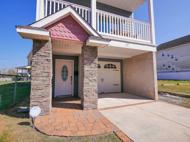 entrance to property featuring a balcony, a garage, and a yard