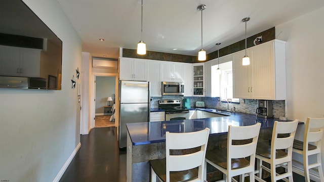 kitchen featuring decorative backsplash, stainless steel appliances, a breakfast bar, hanging light fixtures, and white cabinetry