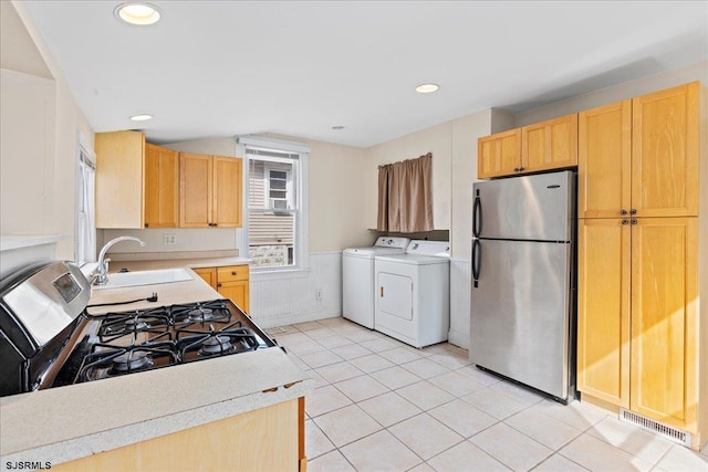 kitchen with stainless steel appliances, light brown cabinets, sink, washing machine and clothes dryer, and light tile patterned floors