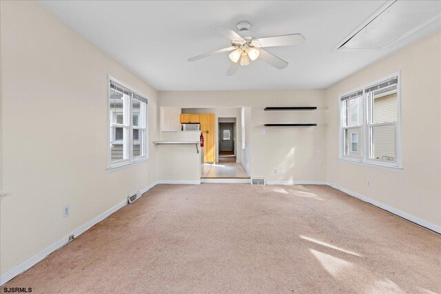 empty room with ceiling fan, plenty of natural light, and light colored carpet