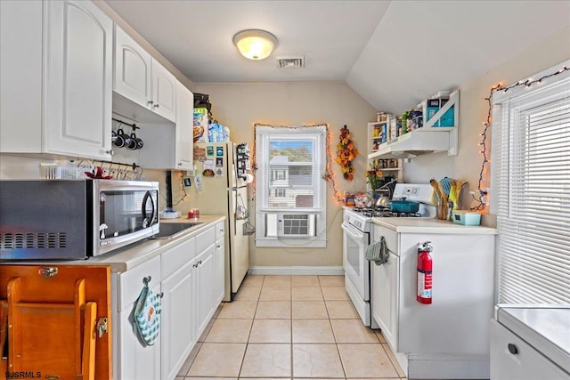 kitchen featuring white appliances, light tile patterned floors, a wealth of natural light, and white cabinetry