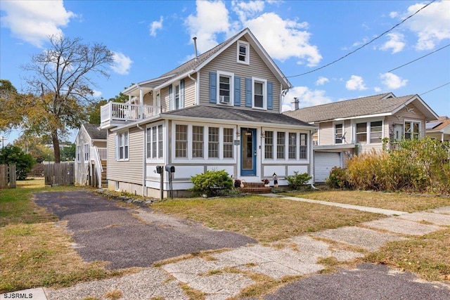 view of front of house featuring a balcony, a garage, a sunroom, and a front lawn