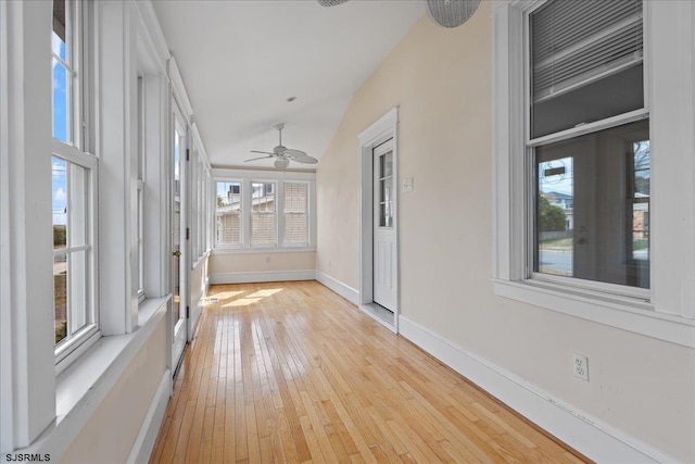 unfurnished sunroom with ceiling fan, plenty of natural light, and vaulted ceiling