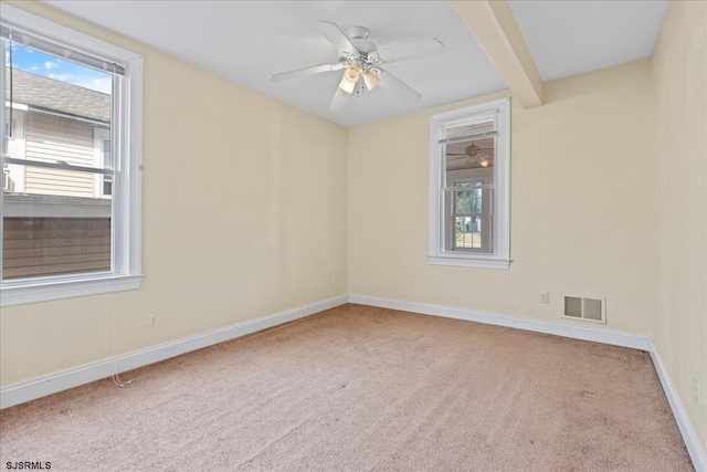 carpeted spare room with beamed ceiling and ceiling fan