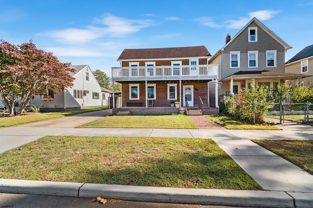 view of front of house featuring a balcony, a front lawn, and covered porch