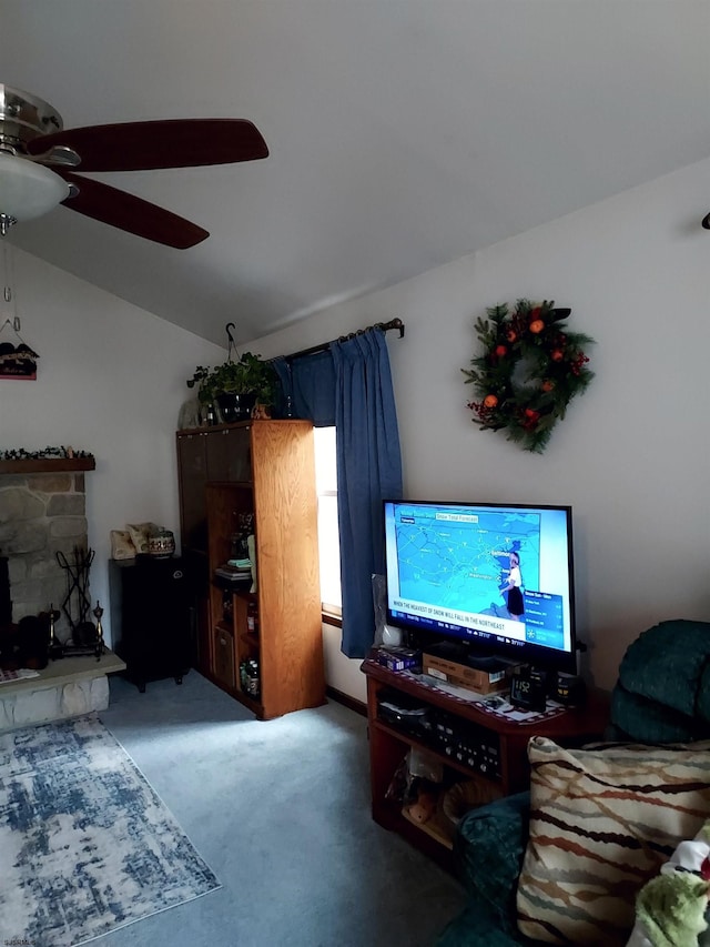 living room with lofted ceiling, carpet floors, a stone fireplace, and ceiling fan