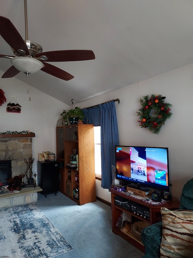 carpeted living room featuring lofted ceiling, a stone fireplace, and ceiling fan