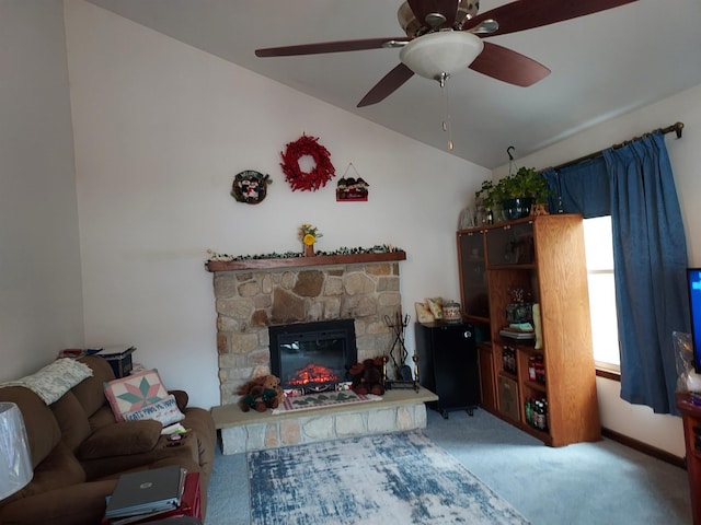 living room featuring ceiling fan, lofted ceiling, a stone fireplace, and carpet