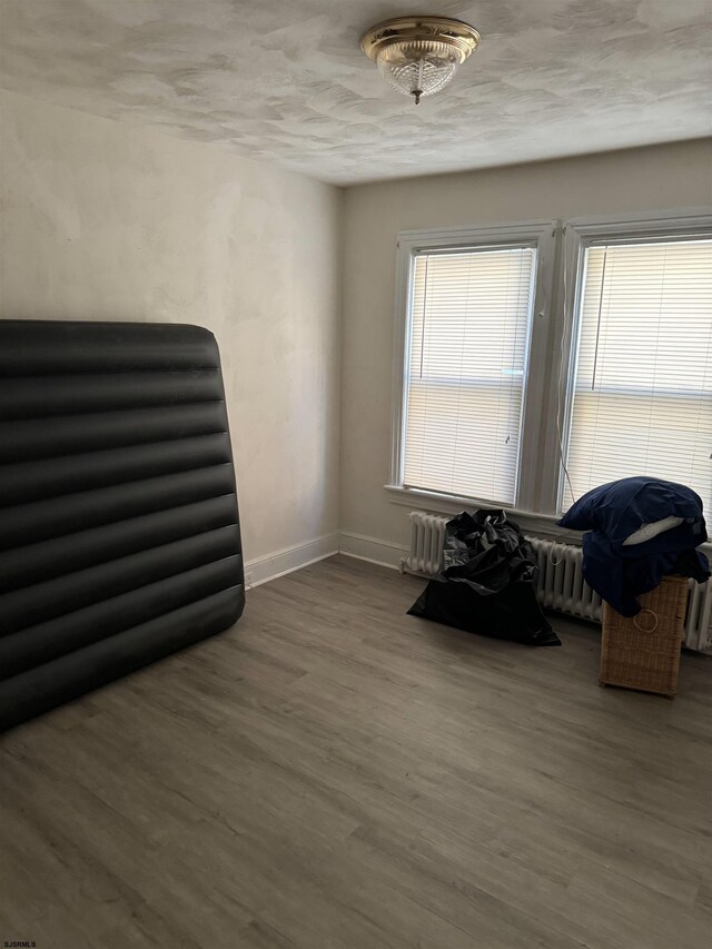 living area featuring radiator, hardwood / wood-style flooring, and a textured ceiling