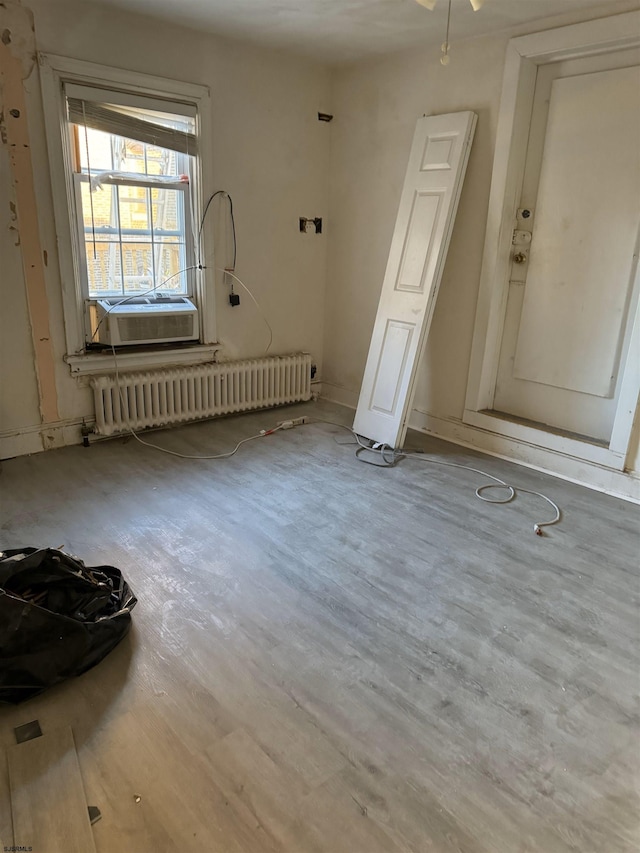 spare room with ceiling fan, cooling unit, light wood-type flooring, and radiator