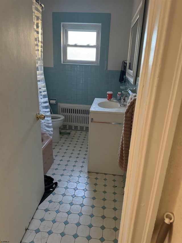 bathroom with tile walls, toilet, vanity, and radiator