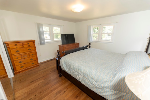 bedroom featuring multiple windows and dark hardwood / wood-style flooring