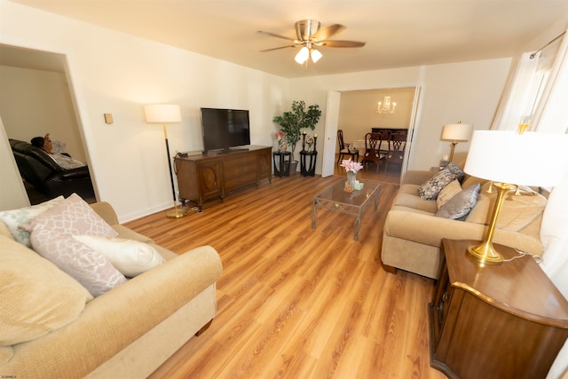 living room with ceiling fan with notable chandelier and light hardwood / wood-style floors