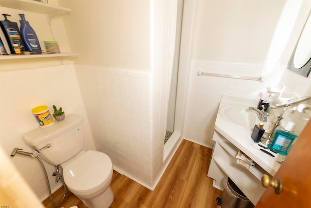 bathroom with walk in shower, toilet, wood-type flooring, tile walls, and vanity