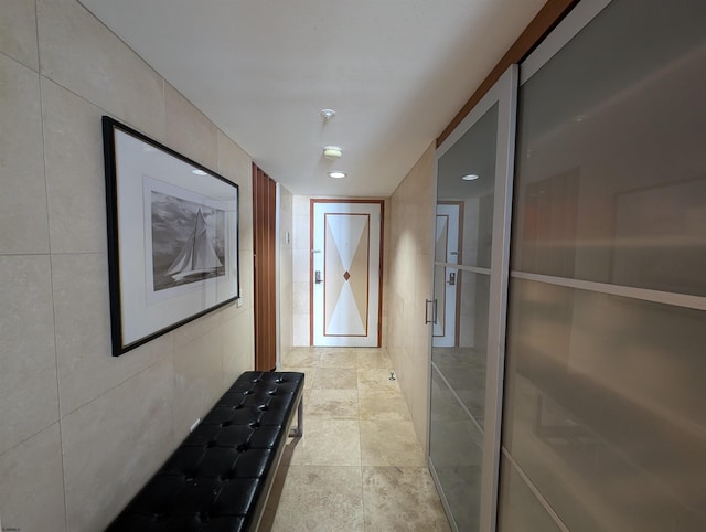 hallway featuring tile walls and light tile patterned floors