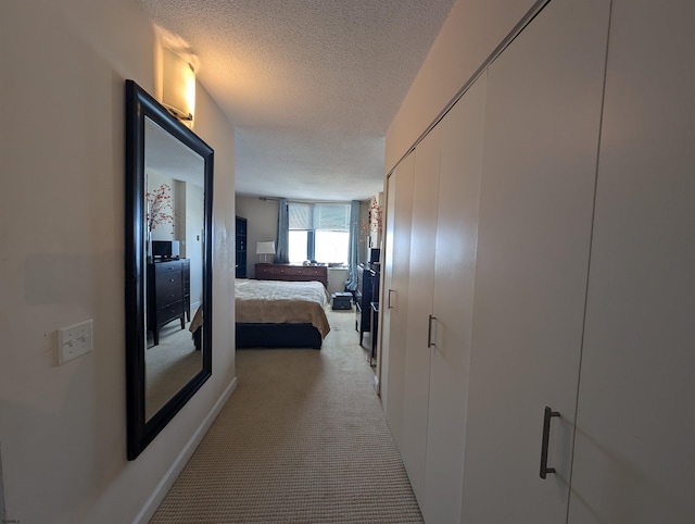 hall featuring light carpet and a textured ceiling