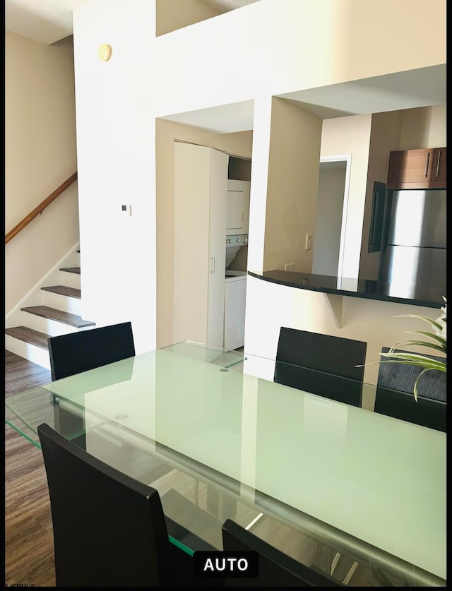 dining area with stacked washer / drying machine and dark hardwood / wood-style floors