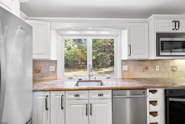 kitchen with backsplash, sink, white cabinetry, appliances with stainless steel finishes, and light stone counters