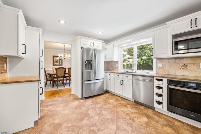 kitchen featuring stone counters, backsplash, stainless steel appliances, white cabinets, and an inviting chandelier