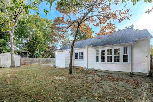 rear view of property with a yard and a storage shed