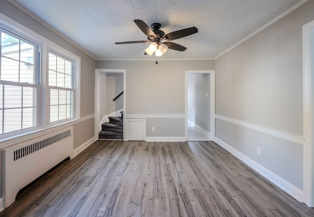 empty room with crown molding, ceiling fan, radiator heating unit, and hardwood / wood-style floors