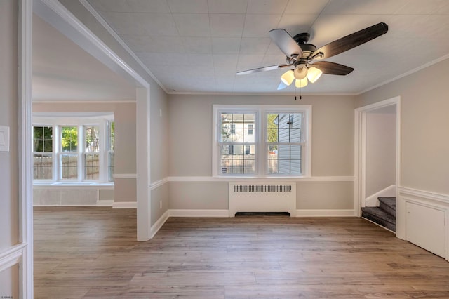 empty room featuring light hardwood / wood-style flooring, radiator heating unit, ornamental molding, and ceiling fan