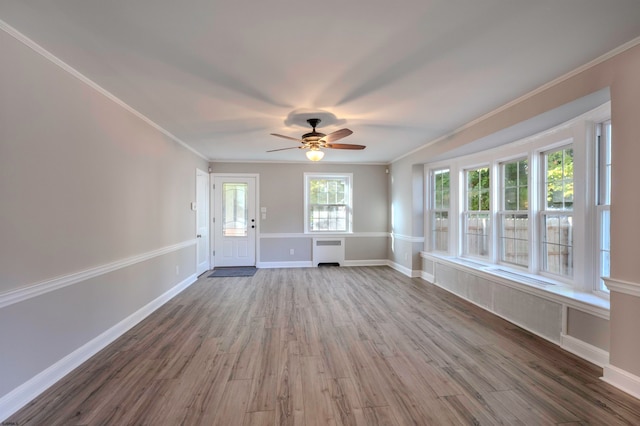 unfurnished living room with ceiling fan, ornamental molding, wood-type flooring, and radiator