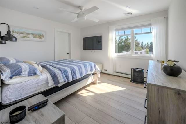 bedroom with ceiling fan, a baseboard radiator, and light wood-type flooring