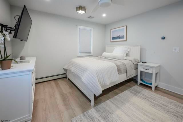 bedroom with hardwood / wood-style floors, ceiling fan, and a baseboard heating unit