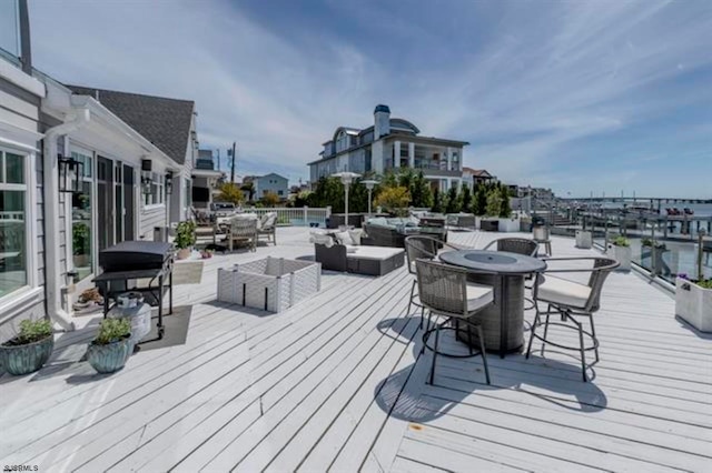 wooden deck with a grill, an outdoor living space, and a water view