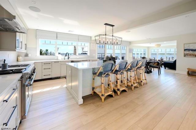 kitchen featuring a breakfast bar, a center island, white cabinets, high end stove, and light hardwood / wood-style floors