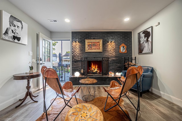 sitting room with hardwood / wood-style flooring and a large fireplace