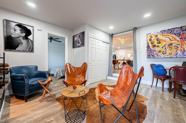 living area with ceiling fan and light hardwood / wood-style flooring