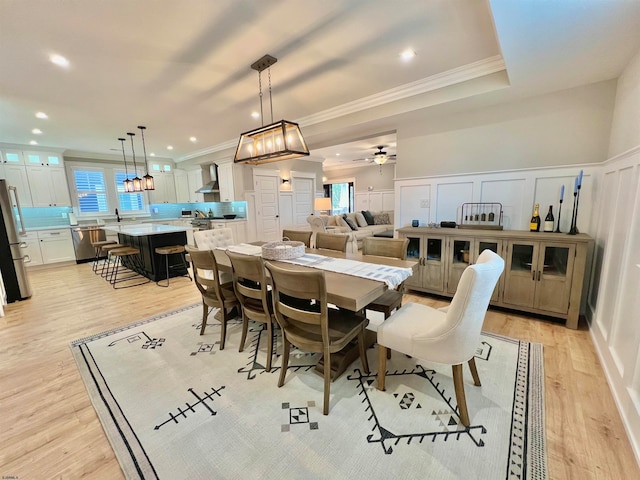 dining room featuring light hardwood / wood-style flooring, ceiling fan with notable chandelier, and crown molding