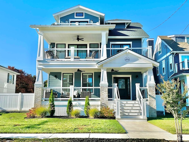 view of front of home with a balcony, covered porch, a front yard, and ceiling fan