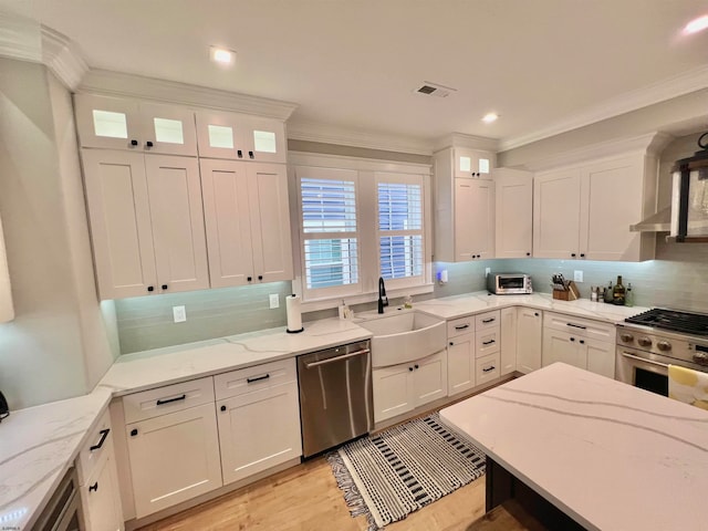 kitchen featuring tasteful backsplash, light stone countertops, sink, white cabinetry, and stainless steel appliances