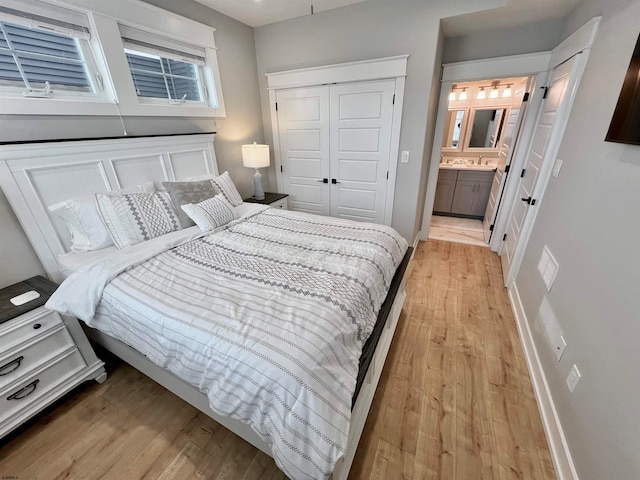 bedroom featuring a closet, connected bathroom, and light hardwood / wood-style flooring