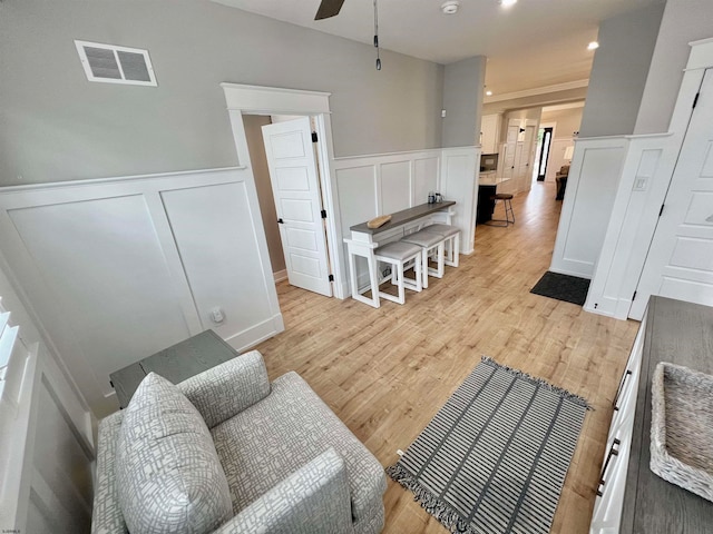 living room with light hardwood / wood-style flooring, crown molding, and ceiling fan