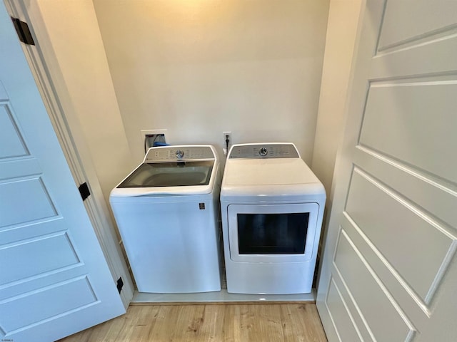 clothes washing area with light hardwood / wood-style flooring and washing machine and clothes dryer