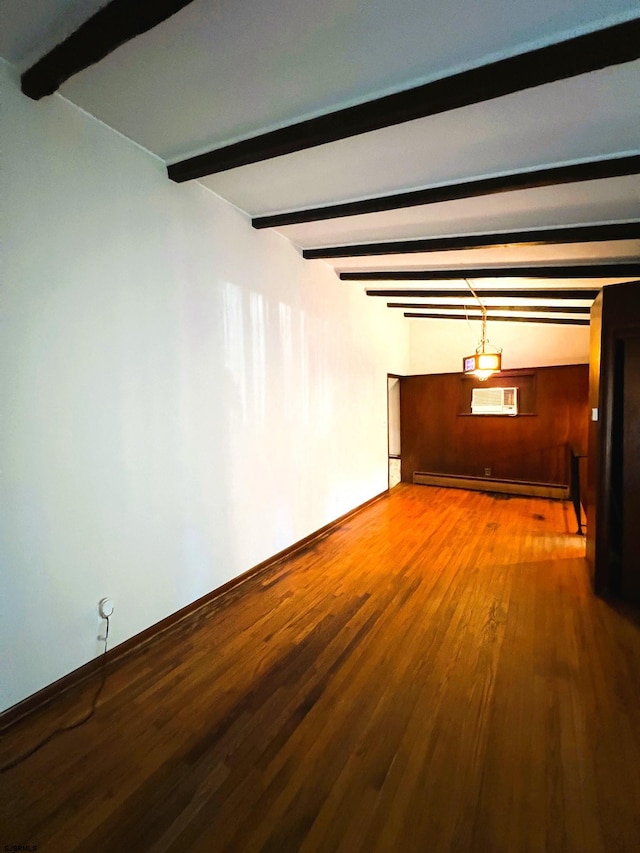 unfurnished room featuring a wall unit AC, beam ceiling, hardwood / wood-style flooring, and baseboard heating