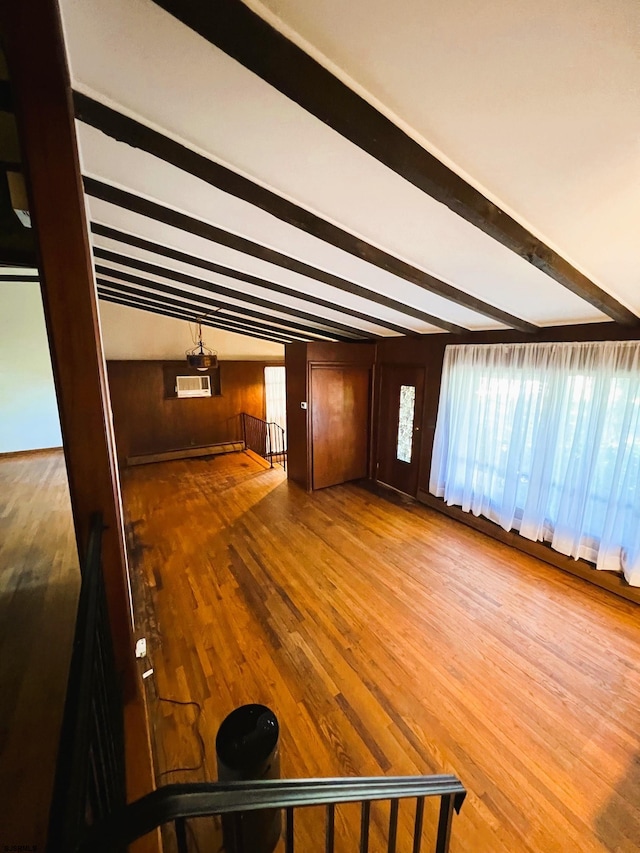 unfurnished living room featuring lofted ceiling with beams, wooden walls, and wood-type flooring