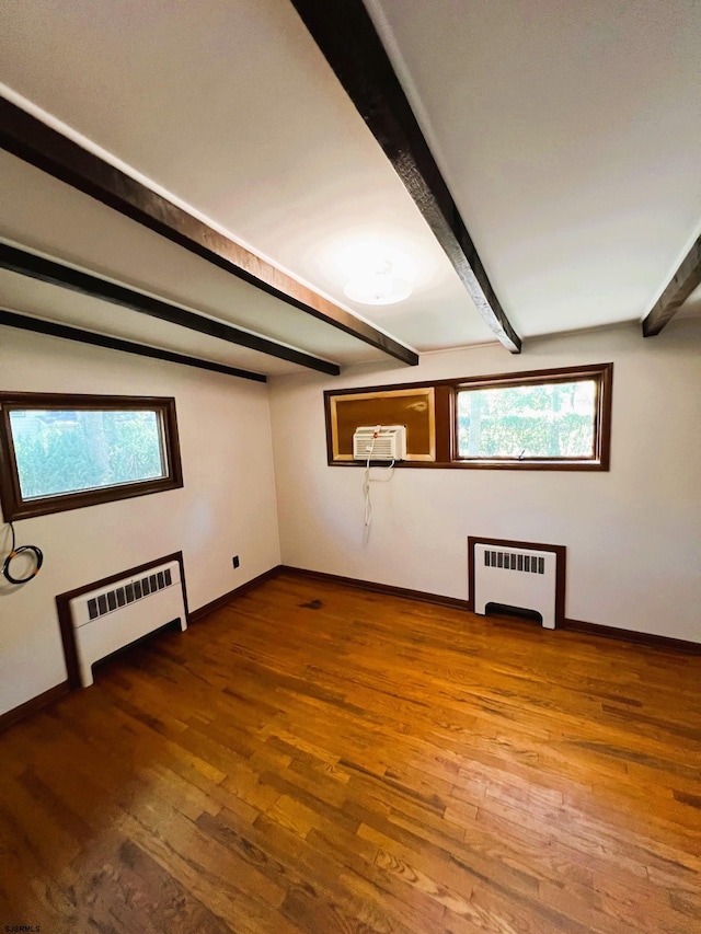 additional living space featuring beam ceiling, hardwood / wood-style floors, and radiator heating unit