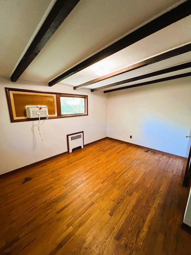 additional living space with radiator, hardwood / wood-style flooring, beamed ceiling, and a wall mounted air conditioner