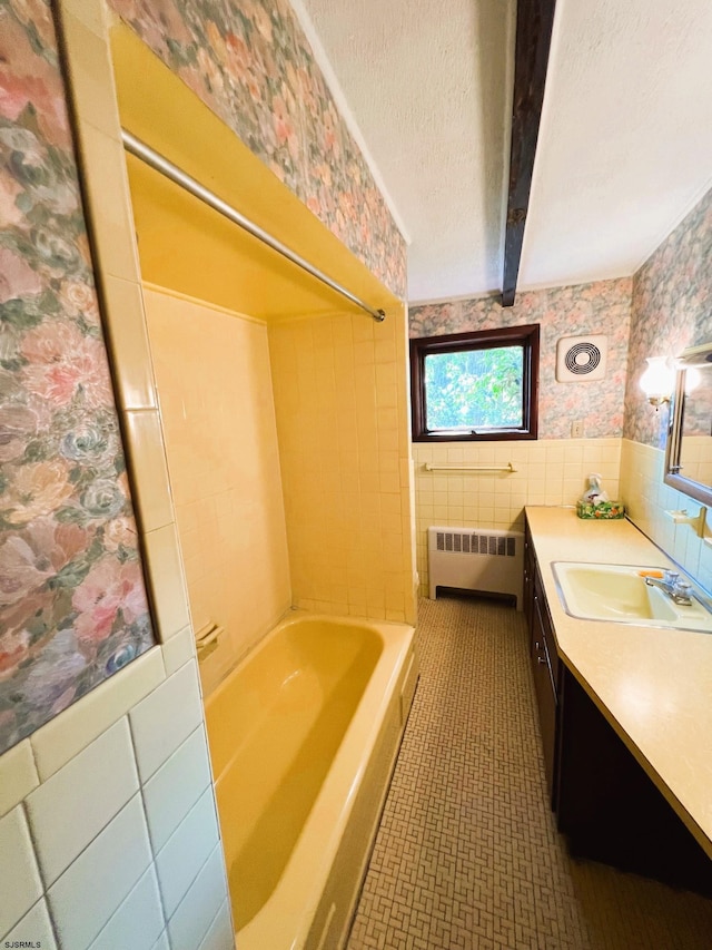 bathroom with radiator heating unit, beam ceiling, tile walls, vanity, and shower / bath combination