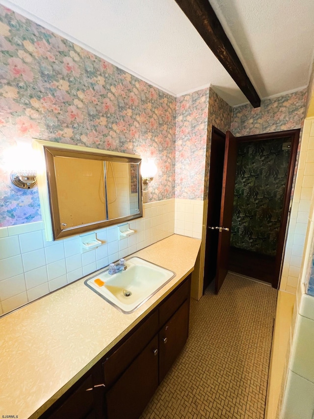 bathroom with vanity, beamed ceiling, and tile walls