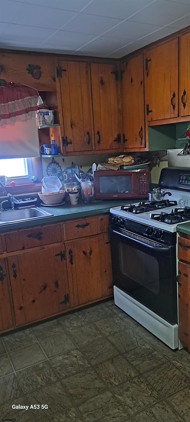 kitchen featuring sink, white range with gas stovetop, and a drop ceiling