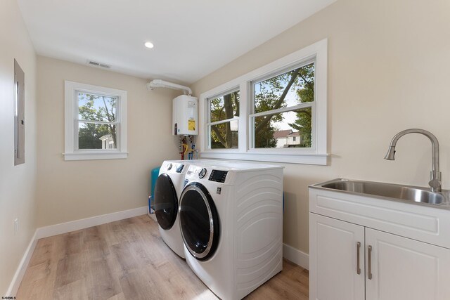 clothes washing area with sink, tankless water heater, a wealth of natural light, and washer and clothes dryer