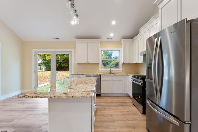 kitchen featuring white cabinetry, light wood-type flooring, stainless steel appliances, sink, and a center island